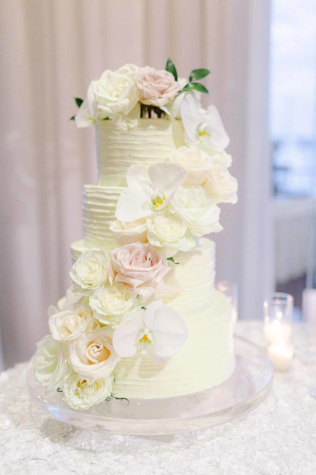four tiered white wedding cake with white roses