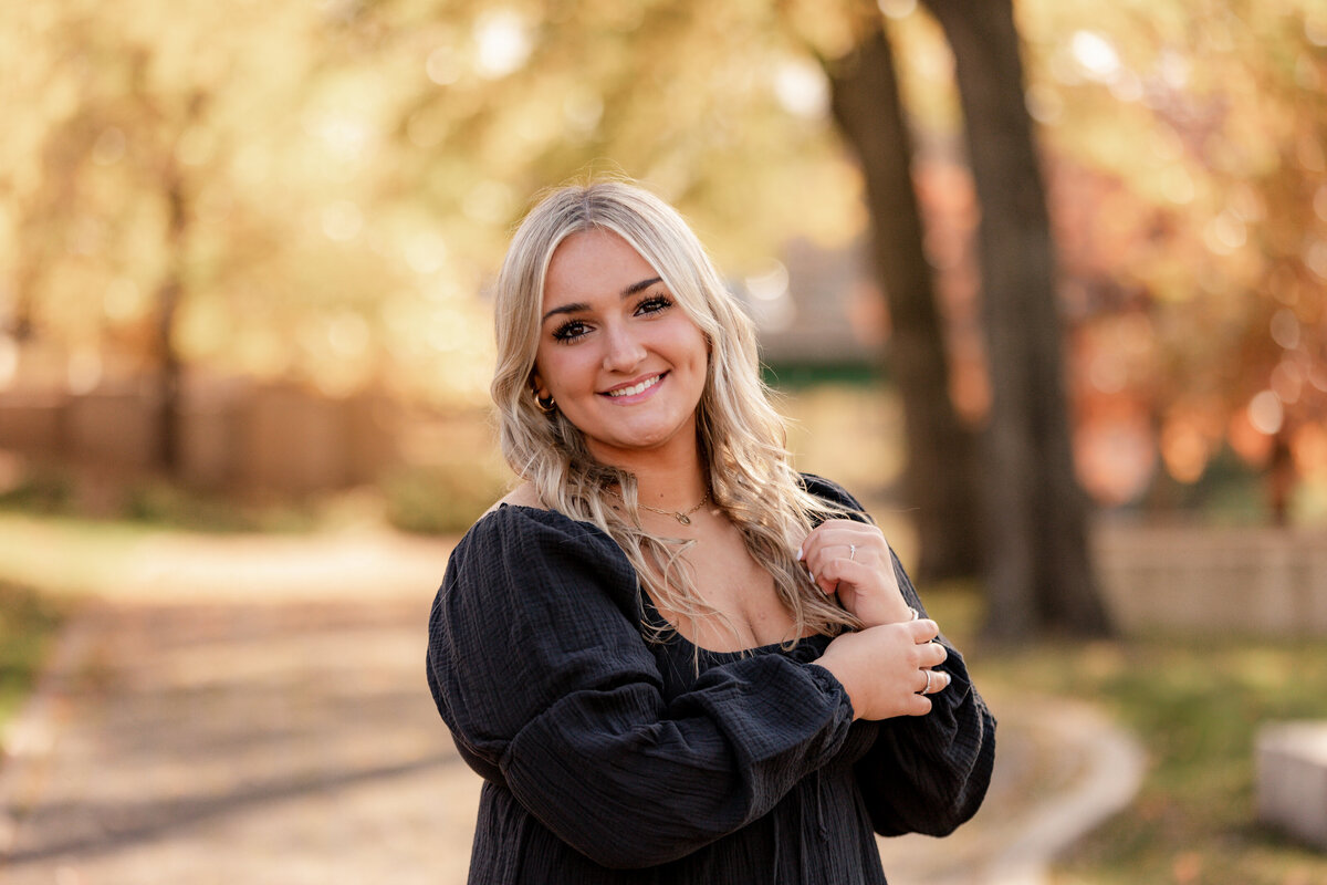 A senior portrait session of a girl in a black shirt playing with her hair.