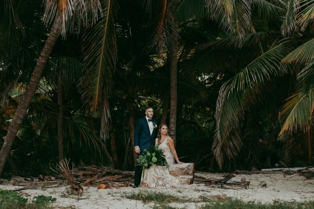 bride and groom on beach surrounding by palms