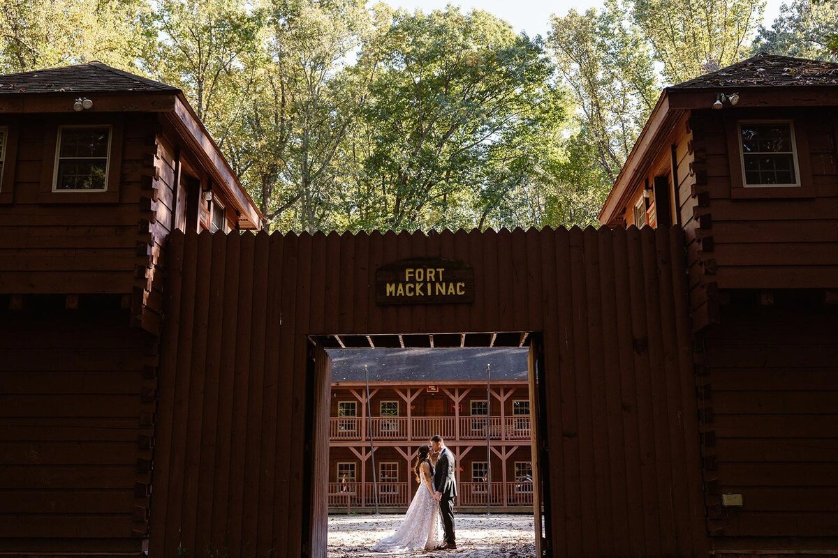 A couple stands facing each other in front of the fort at Puh'Tok Camp