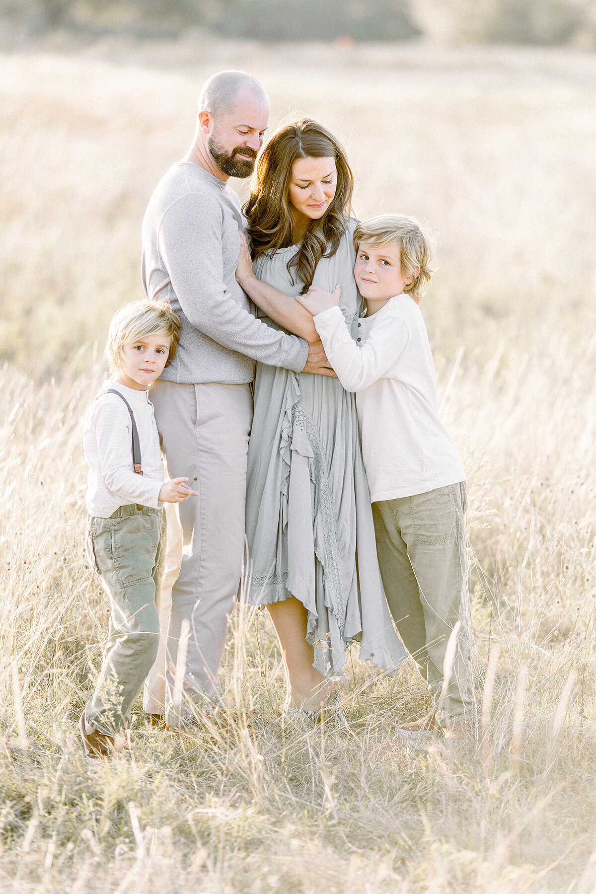 A Frisco family standing in a local park field as they hold each other and pose for family photos.