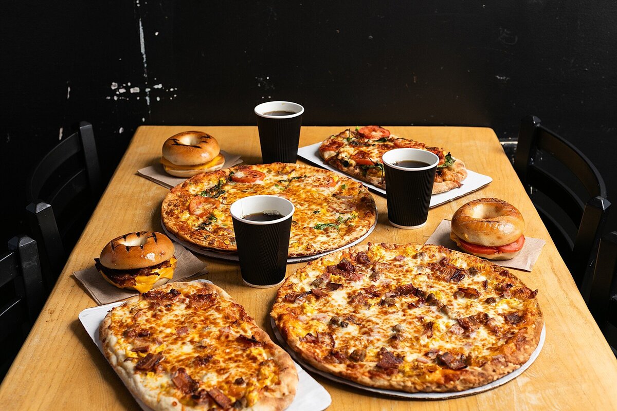 breakfast sandwiches and pizzas with coffee spread out on a table for breakfast
