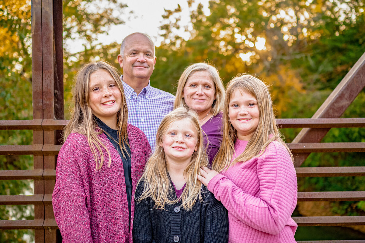 A family of five pose together on a bridge for family pictures in Hayes Nature Preserve in Alabama