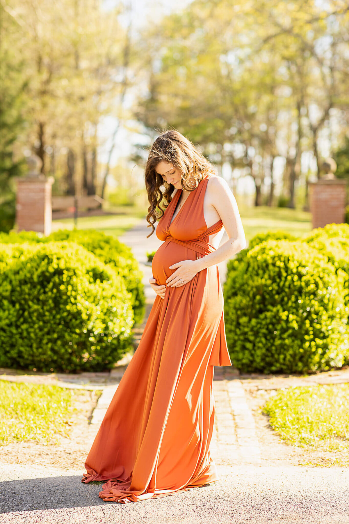 Expectant mom in a burnt orange dress in a garden