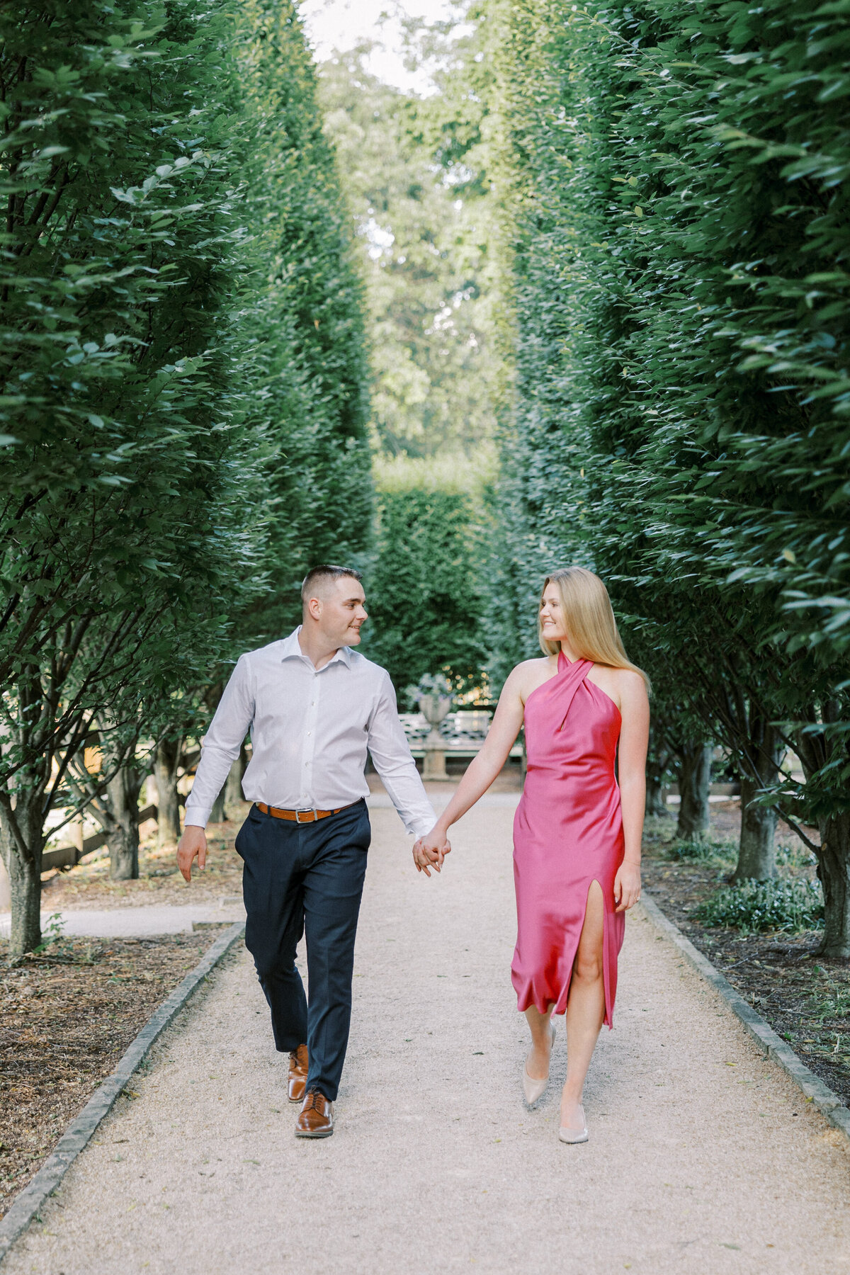 Engaged couple walking hand-in-hand on tree-lined path in Columbus park shot by Philadelphia photographer.