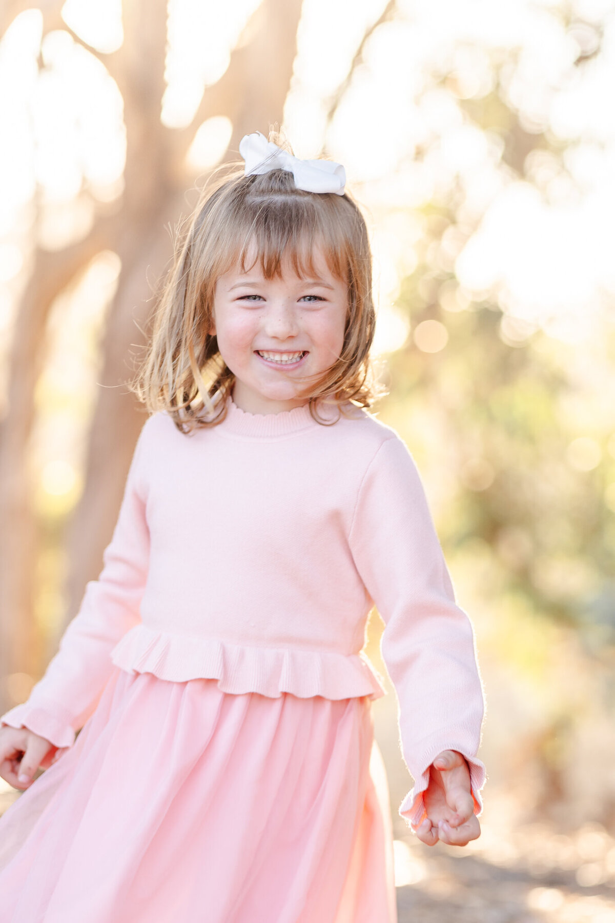 little girl in a pink dress smiling at the camera