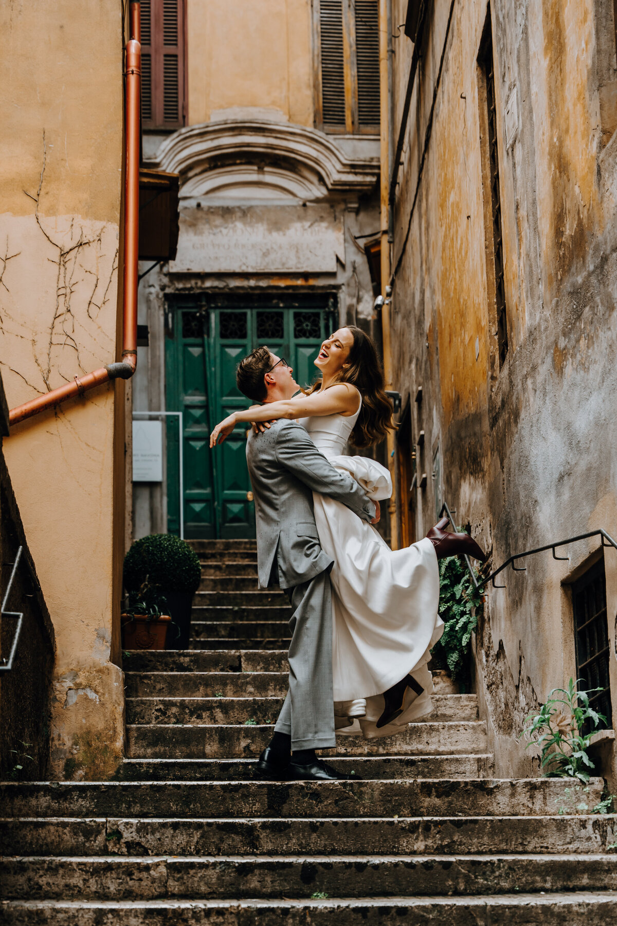 Groom lifting the bride through cobblestone alley in Rome.