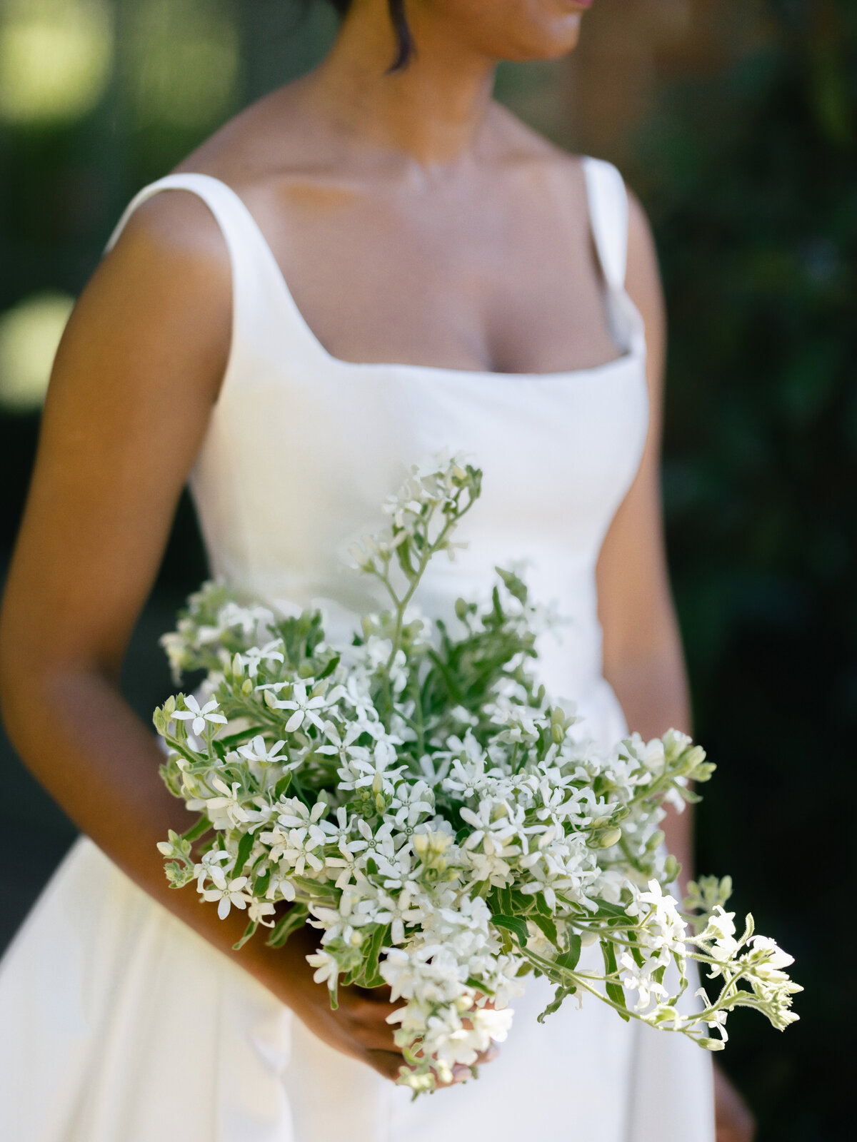 bride holding simple and small scale, single ingredient bouquet made of tweedia rather than lily of the valley