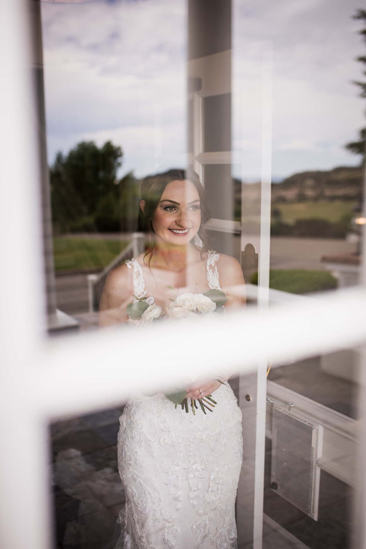 A shot of a bride through a glass window as she waits to see her groom for the first time.