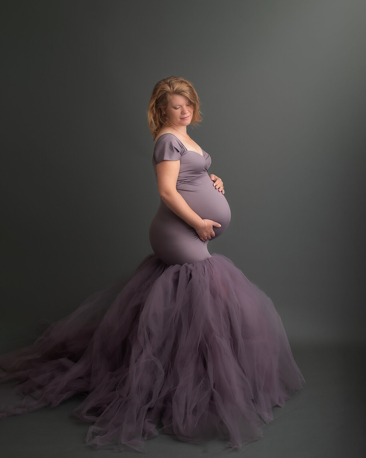mom expecting a baby in purple gown at maternity photo session