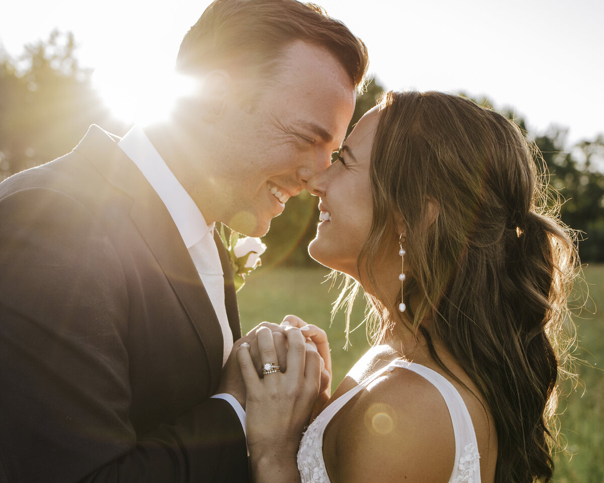 A radiant newlywed couple sharing an intimate moment, with the setting sun casting a warm, golden glow on their joyful smiles taken by jen Jarmuzek photography a Minneapolis wedding photographer
