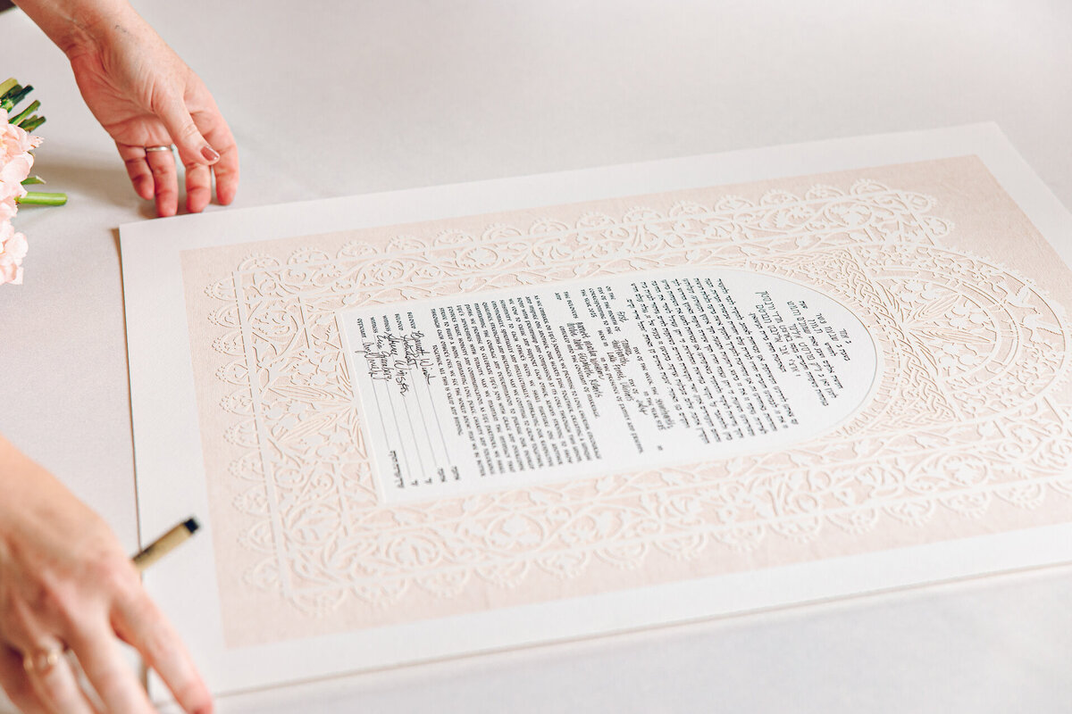 A couple signs their ketubah before their Jewish ceremony at Armour House in Lake Forest.