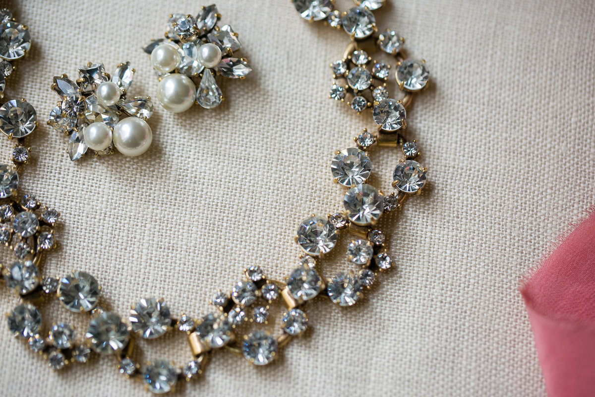 Close up photo of the bride’s jewelry, faux diamonds and pearls.