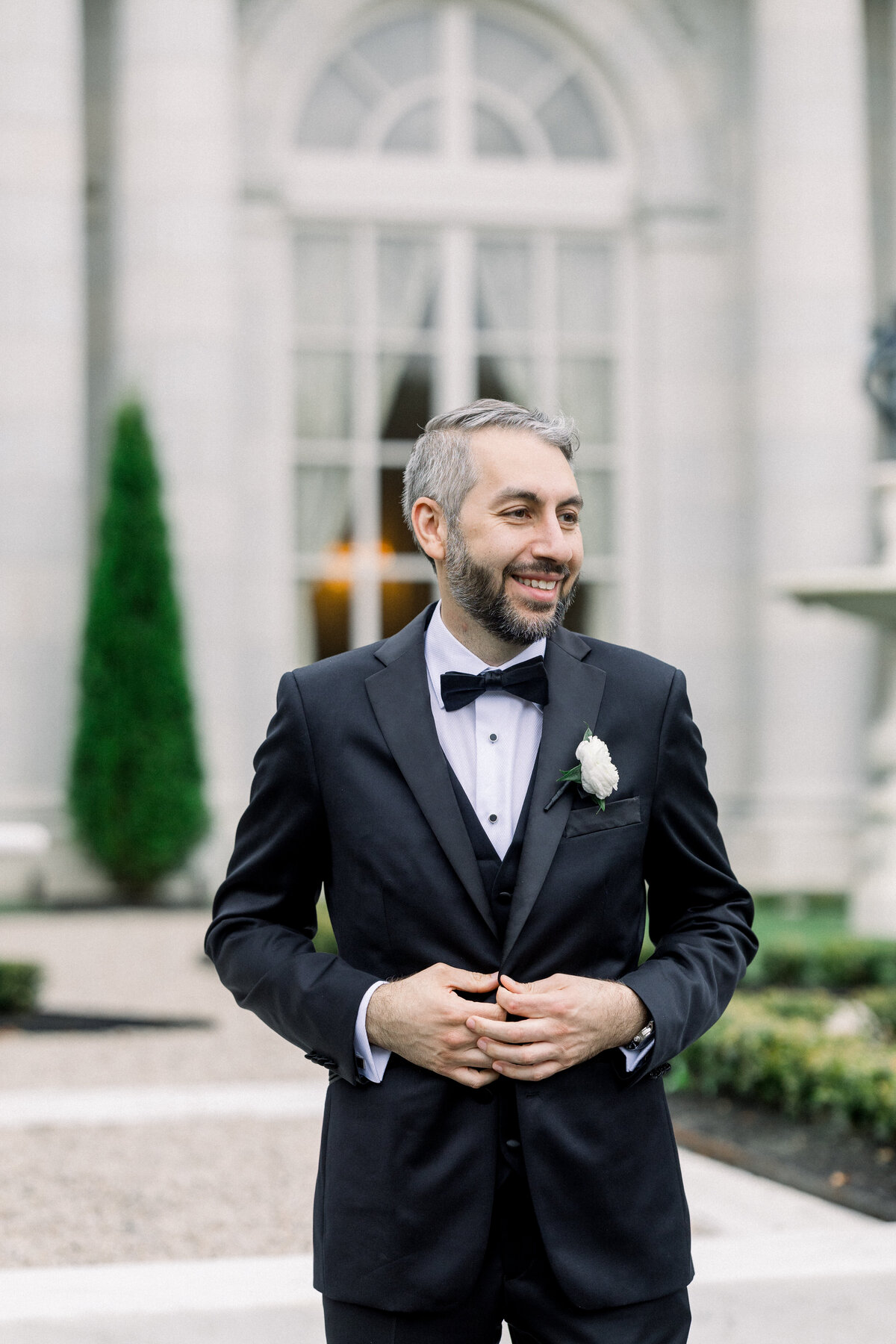 sophisticated groom poses for debonair groom portrait outside of rosecliff mansion in newport rhode island