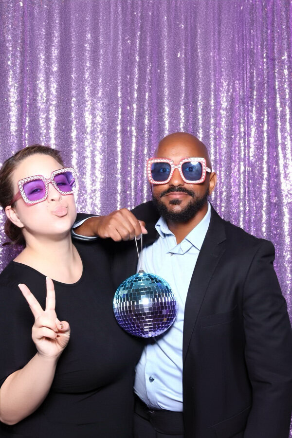 Mente Bezuneh and Makenzie Harris from Mentopia Weddings posing for a photo booth with a sparkle ball.