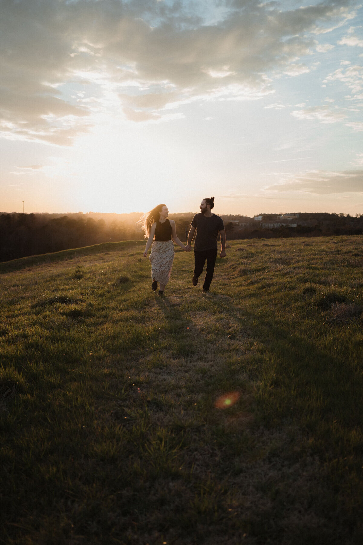 couple running on a hill at sunset