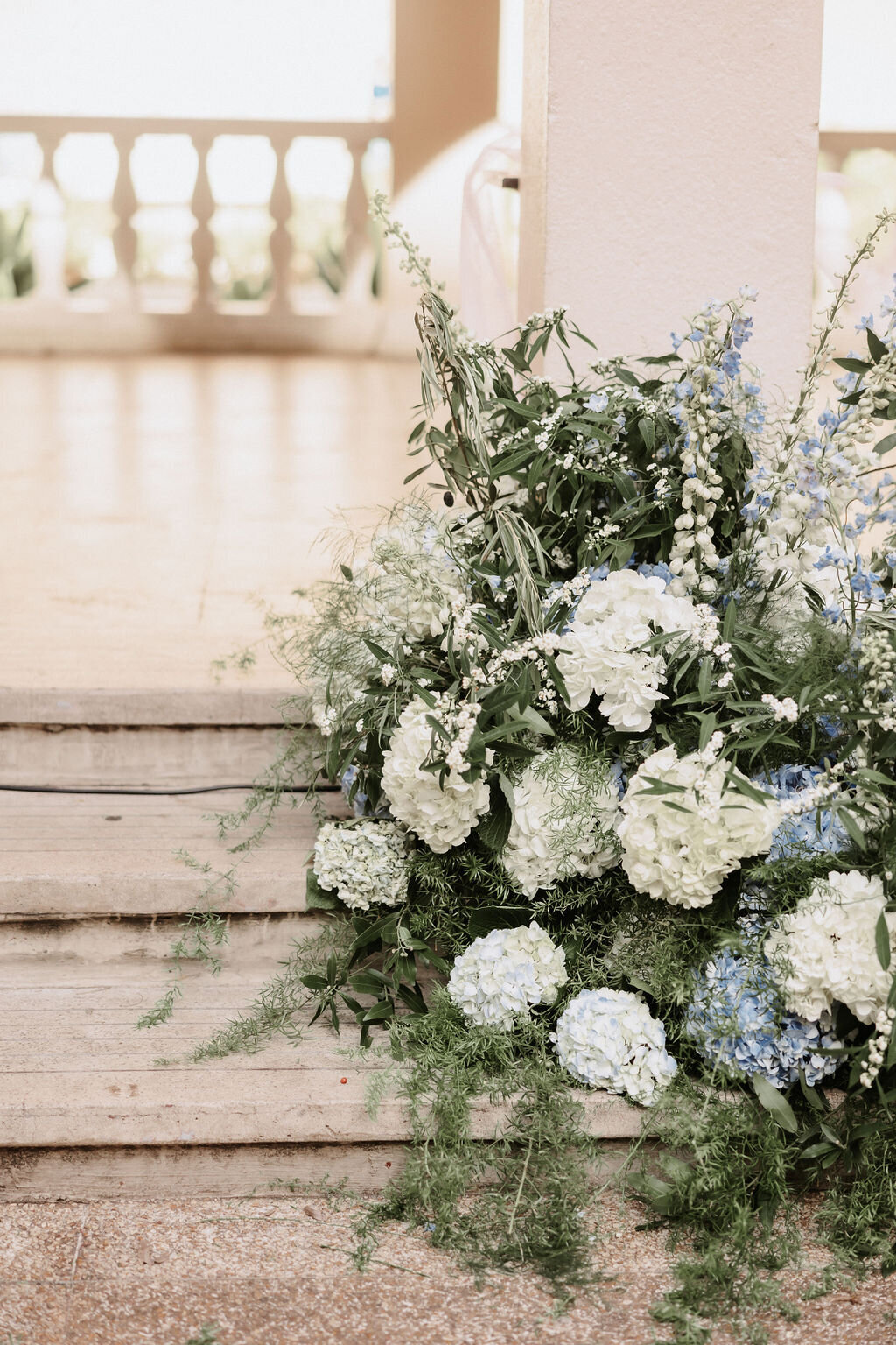 ceremony wedding flowers that are white and blue with greenery draping down
