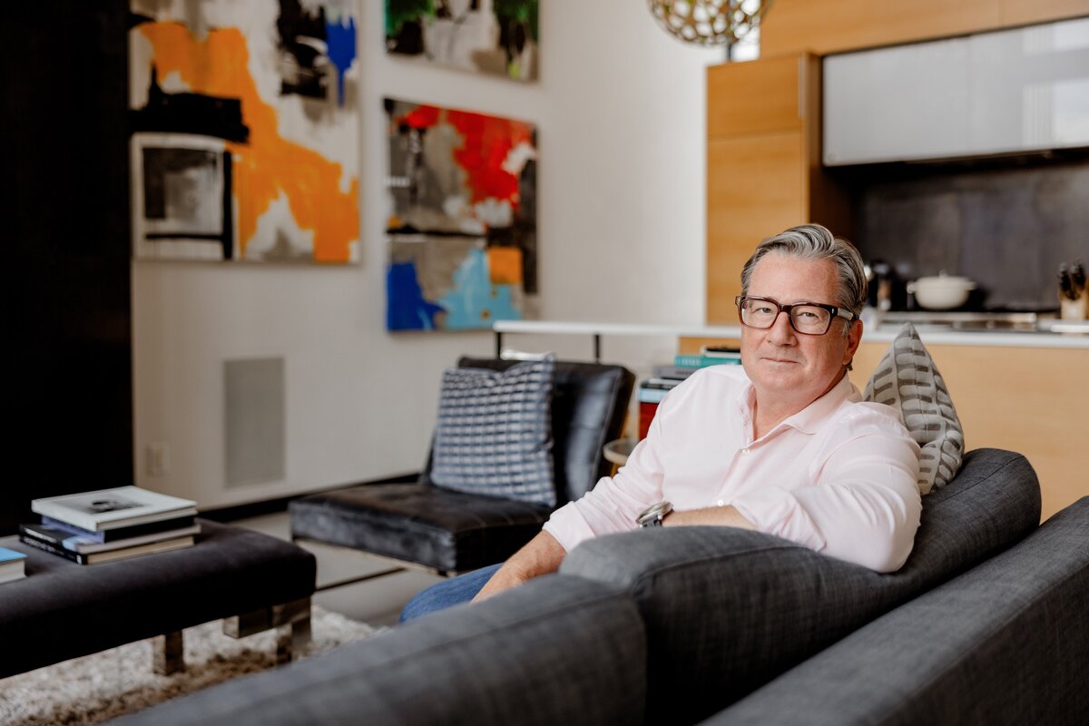 man in his home surrounded by beautiful artwork poses for headshot