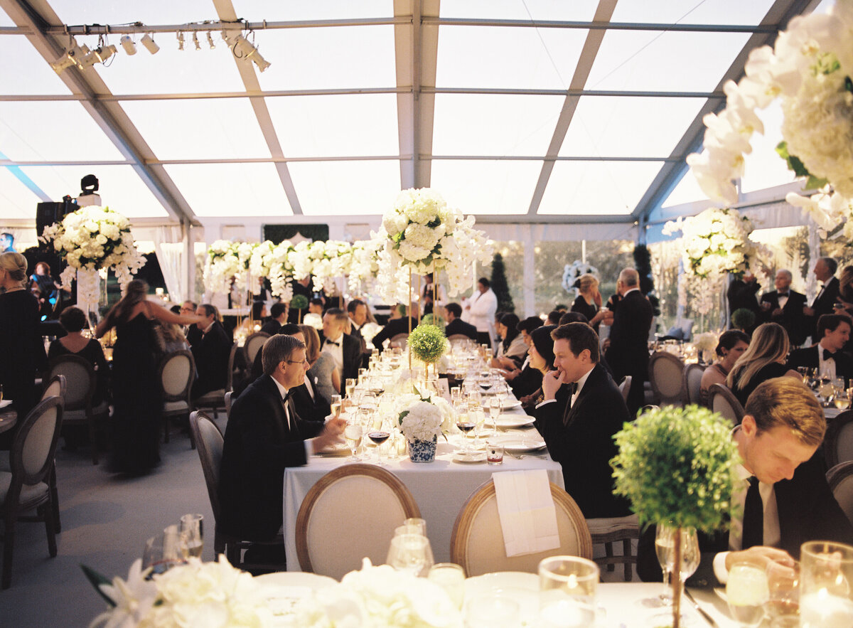 A picture of the wedding guests at the reception sitting at the table. 
