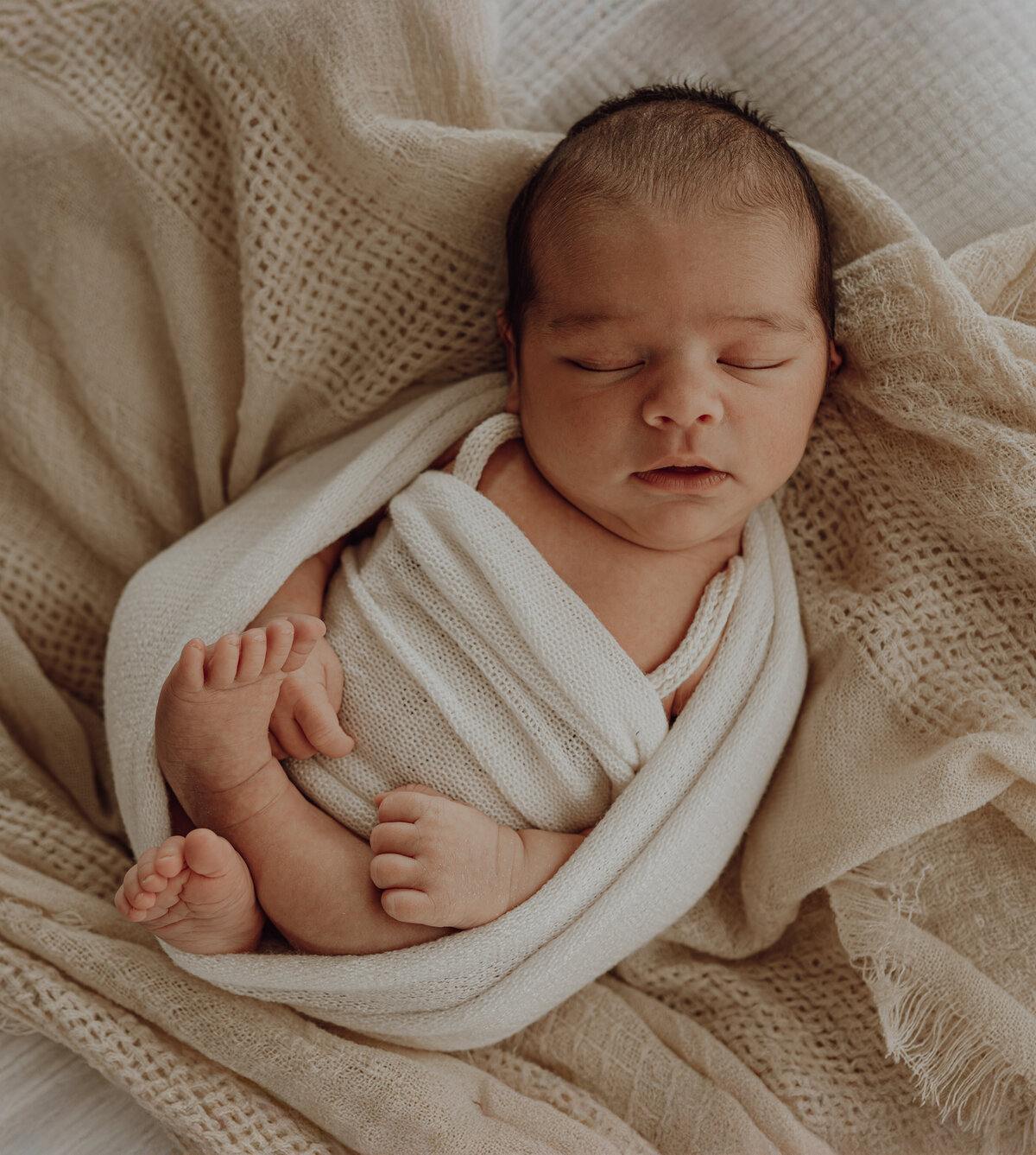 Baby slaapt in wikkeldoek tijdens newborn fotoshoot