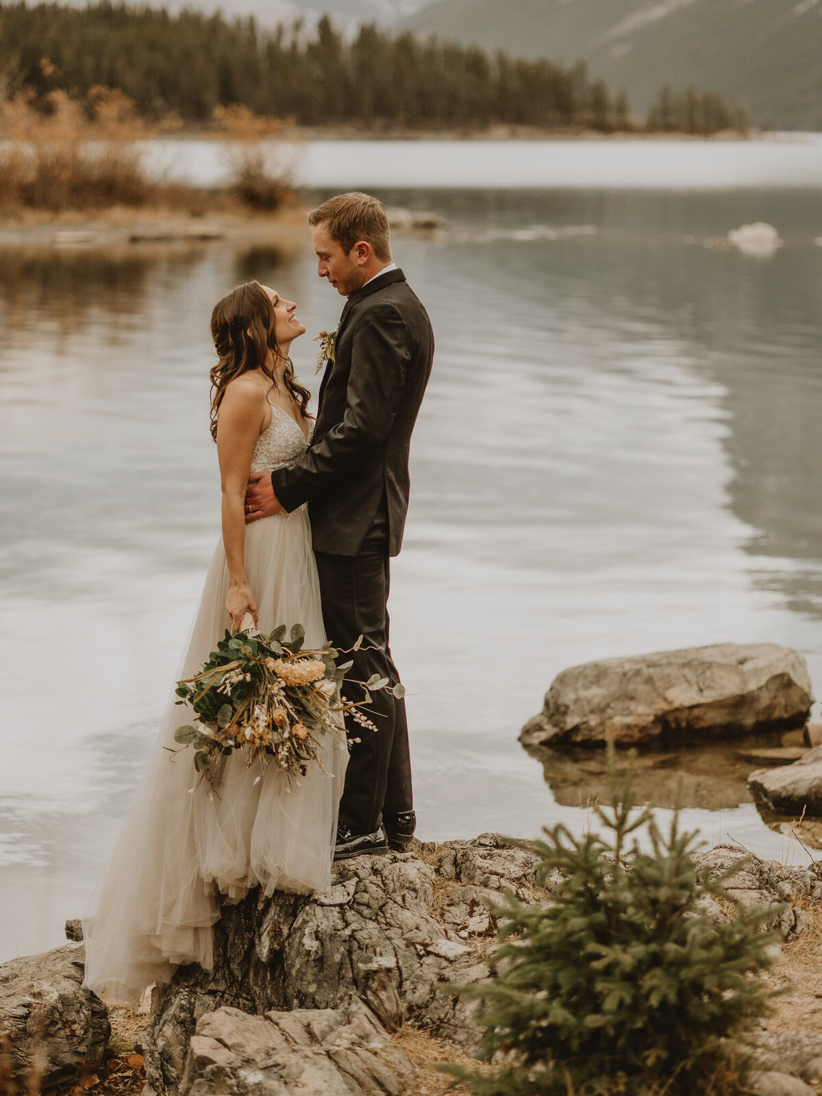 Bride and groom looking at one another at lake minnewanka, Banff Alberta
