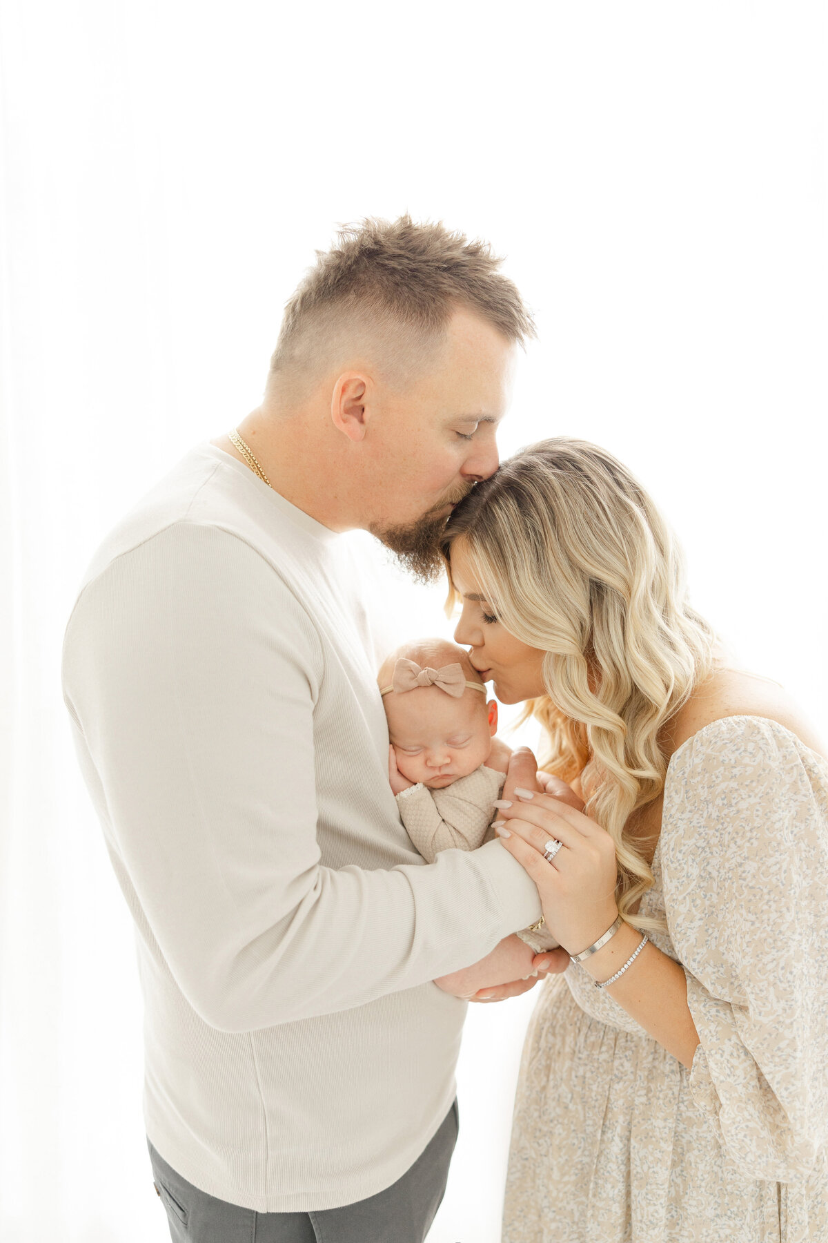 Dad kissing mom while mom kisses baby for dc newborn photos