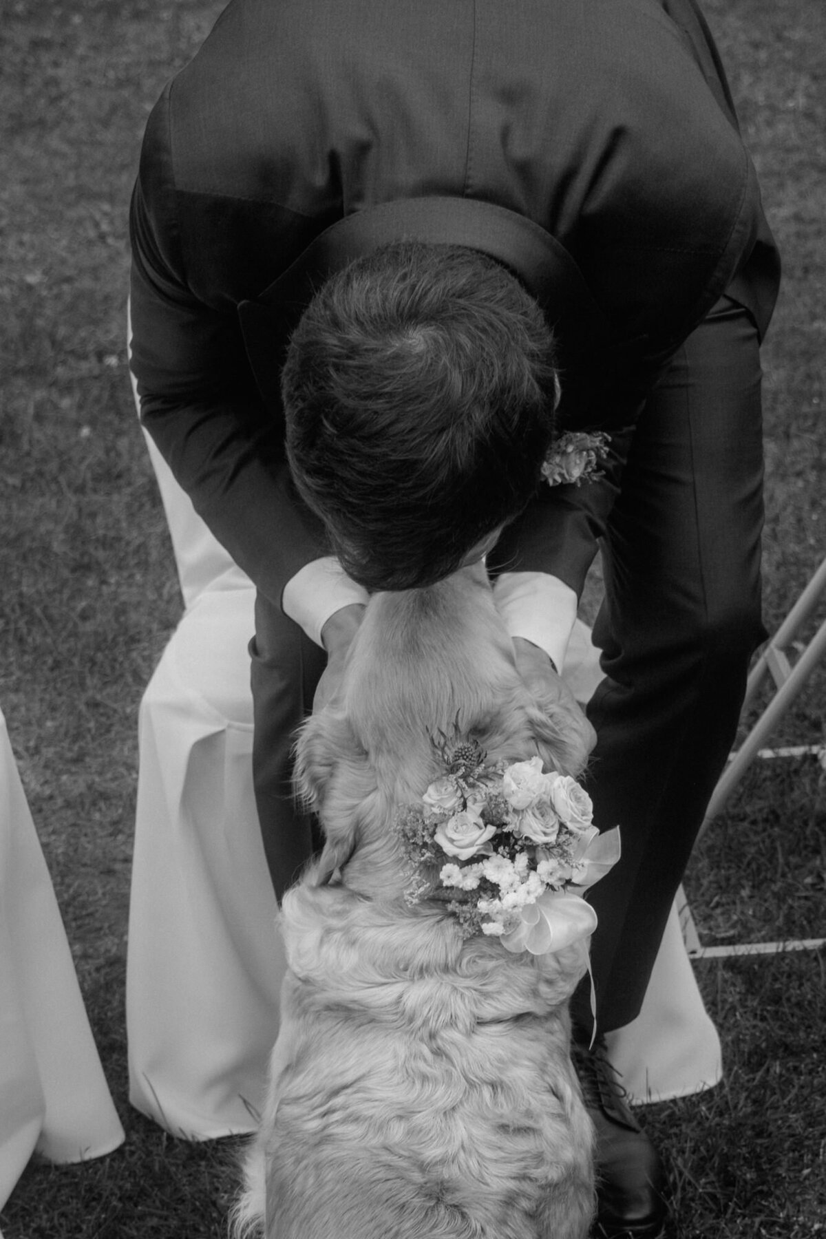 The bride hugs his dog in a black and white candid moment shot.