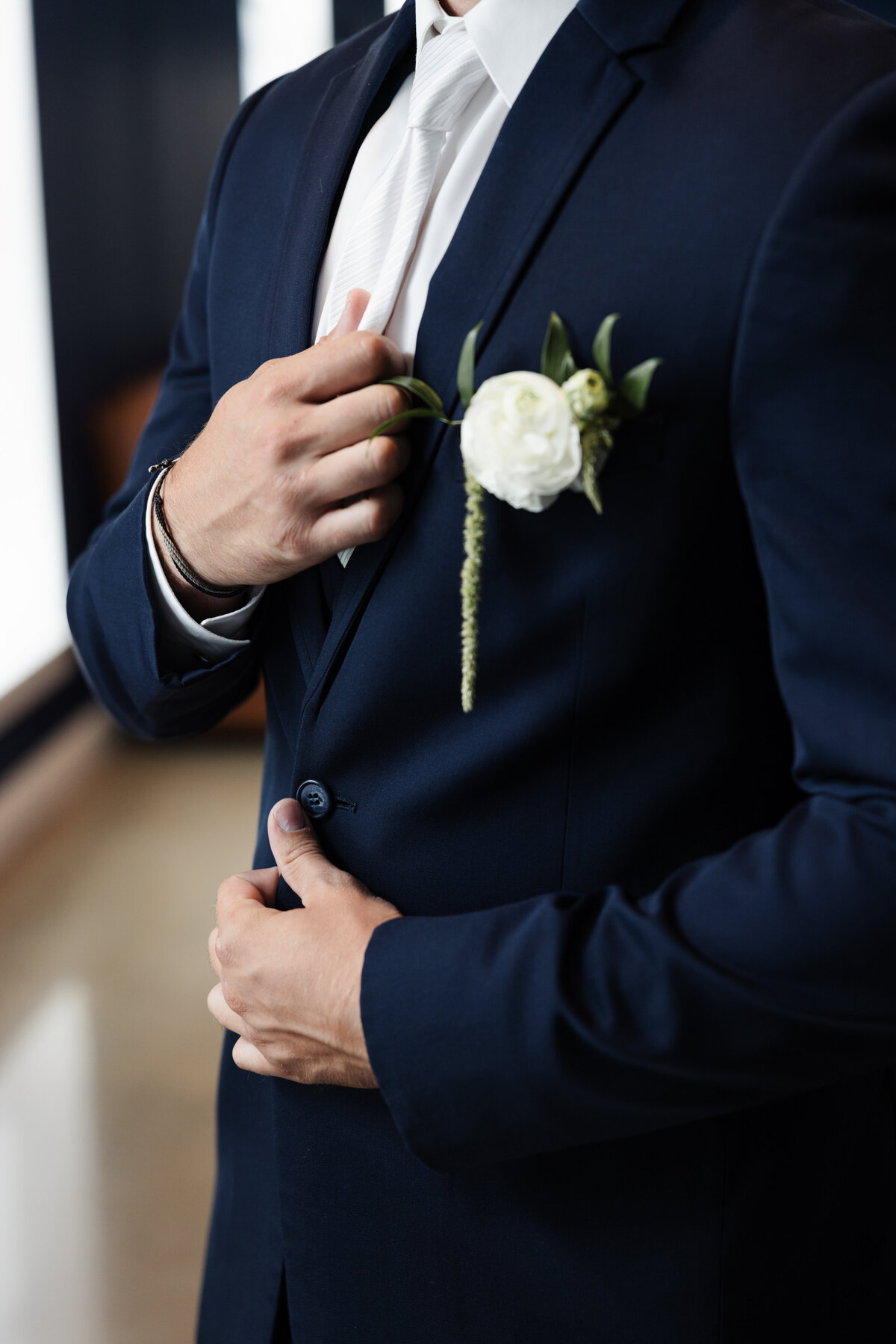 Groom Adjusting Suit Jacket with White Rose Boutonniere