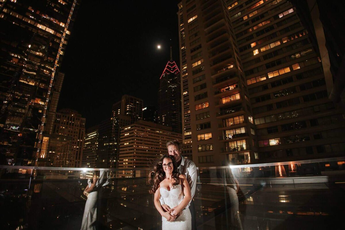 Bride and groom embracing outside in Philadelphia surrounded by tall buildings.