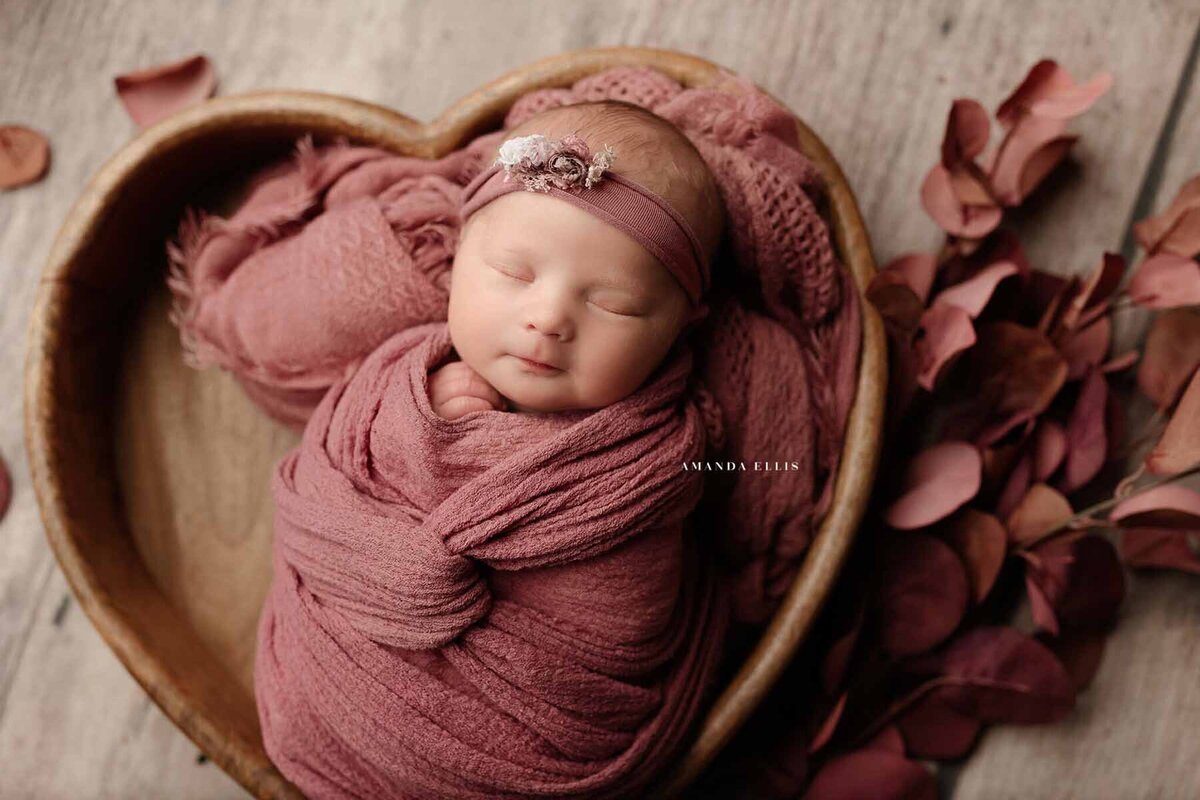 Artistic newborn photography portrait of baby in heart shaped basket