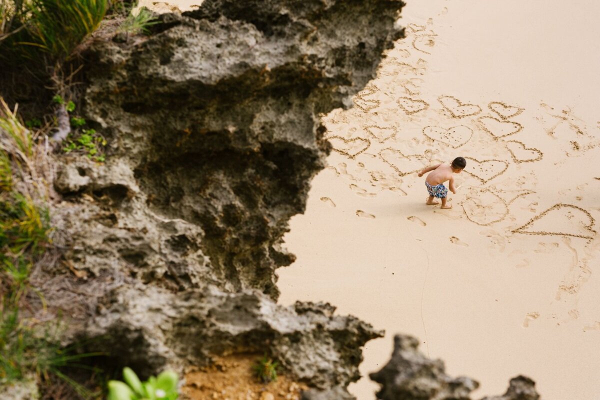 An aerial view of a little boy making shapes in the sand.
