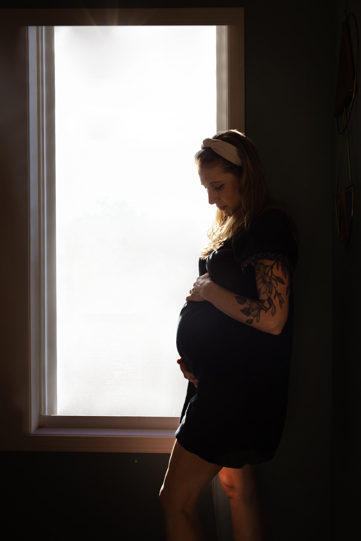 Pregnant woman gazes at her stomach by the window