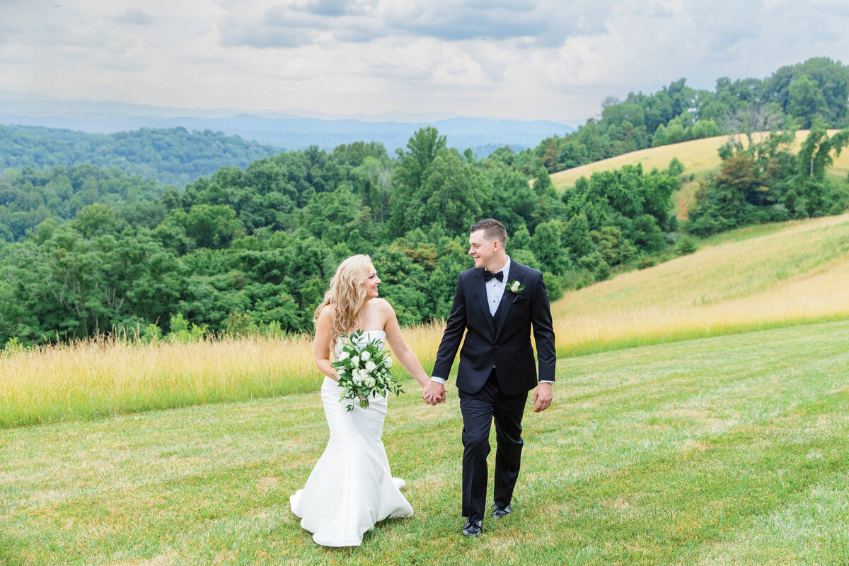 bride and groom walking along mountain ridge