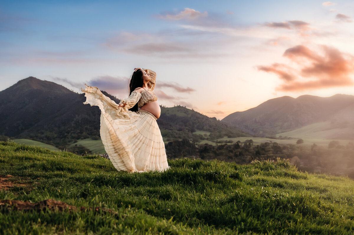 mom in the mt diablo mountains in walnut creek. she wears a 2 piece maternity dress that is blowing in the wind.