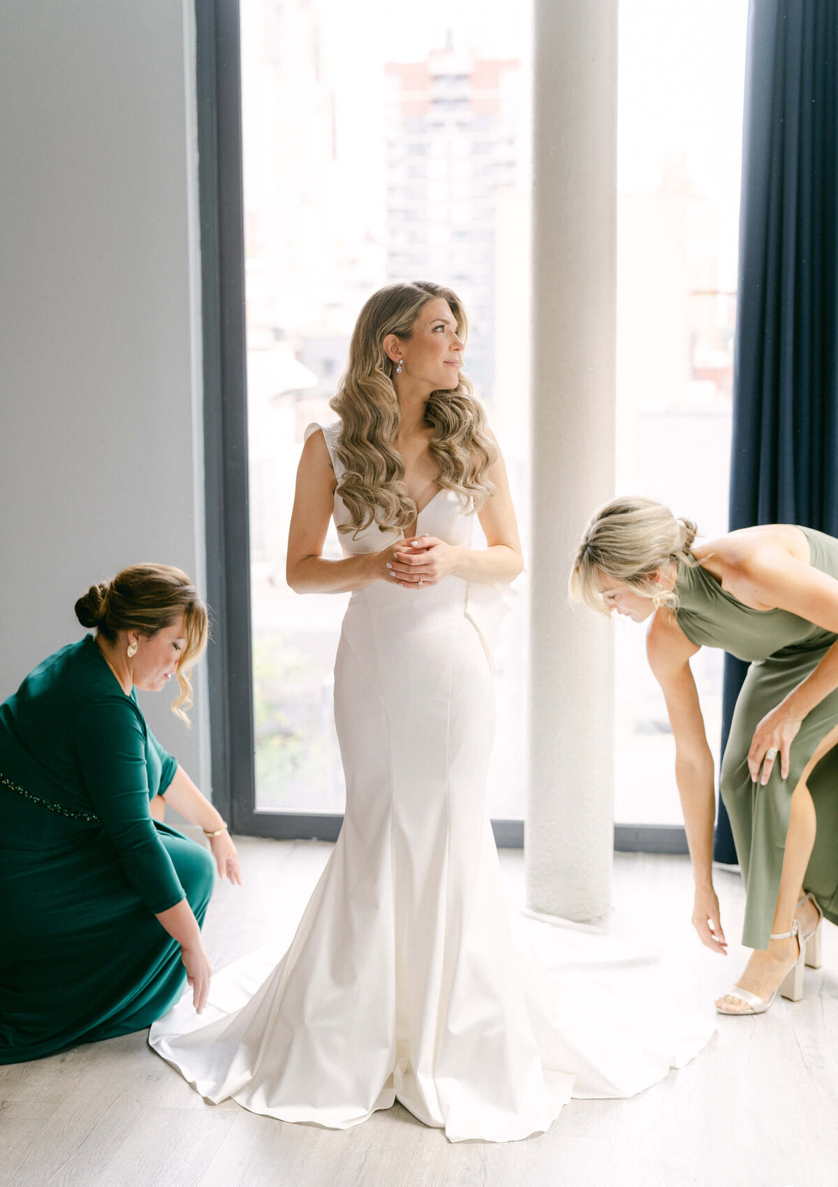 Bride wearing her wedding gown, with bridesmaids fluffing out the train