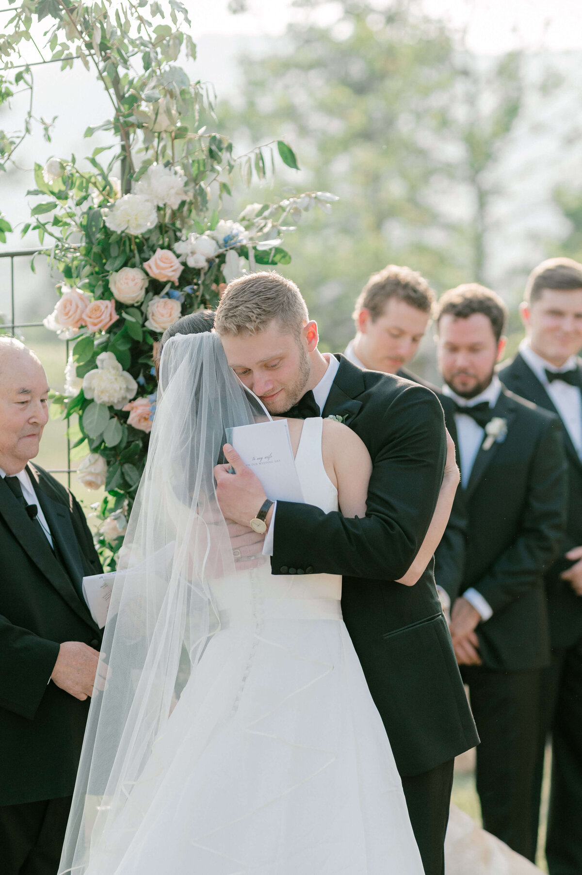 Emotion filled image of a groom hugging his bride after reading their vows to one another, captured by Rachael Mattio