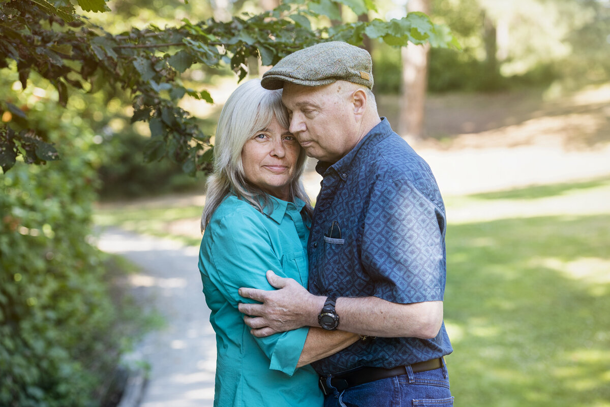 A couple standing close with their arms around each other.