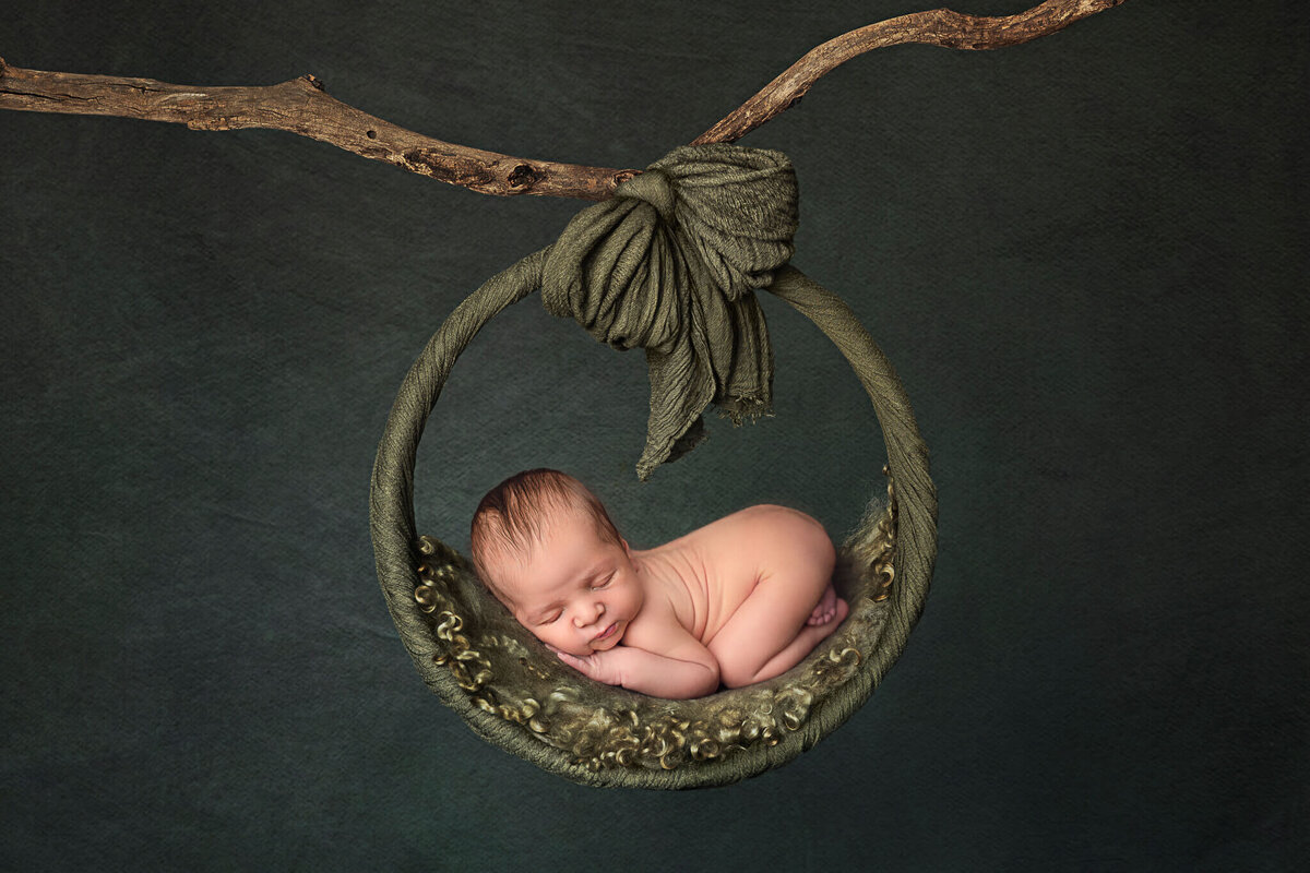Newborn photography in Akron ohio with baby on a green swing.