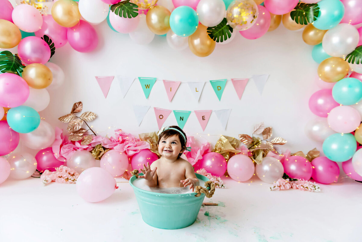 baby girl in a teal bath for her cake smash photography session