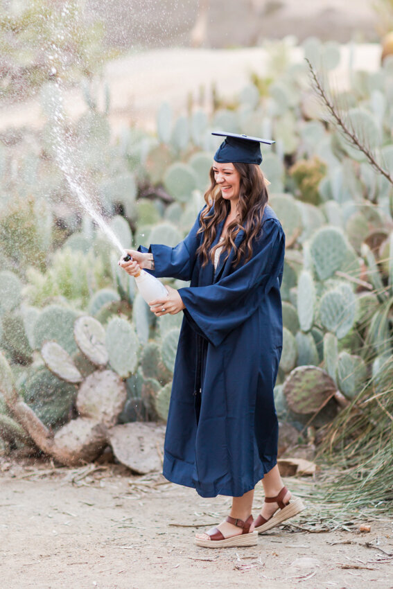 senior girl poppiing champagne in Balboa Park San Diego