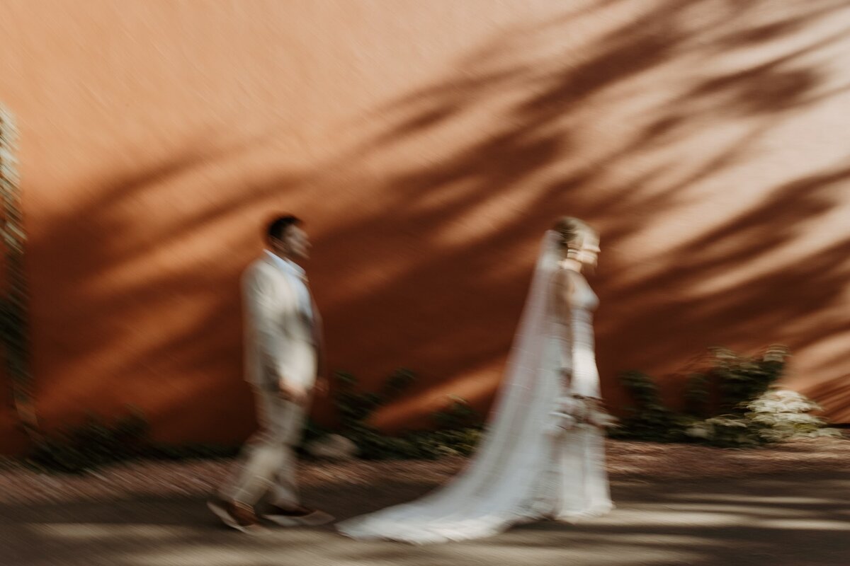 bride and groom walking in front of adobe house