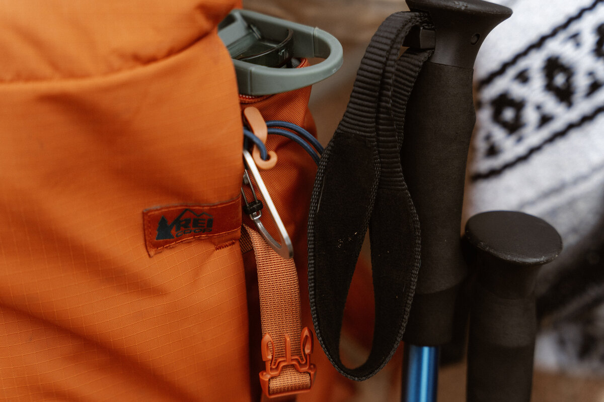 Orange REI day pack with trekking poles and a mexican blanket