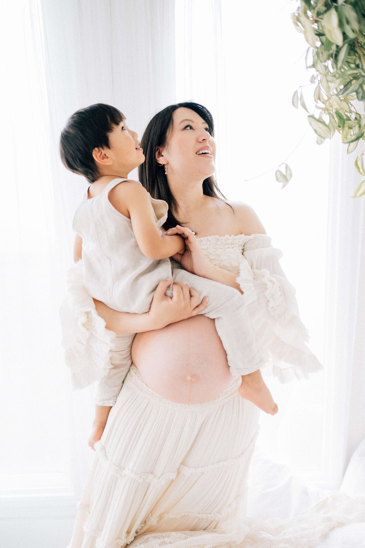 maternity mother holding her child on one hip while looking up at the ceiling 