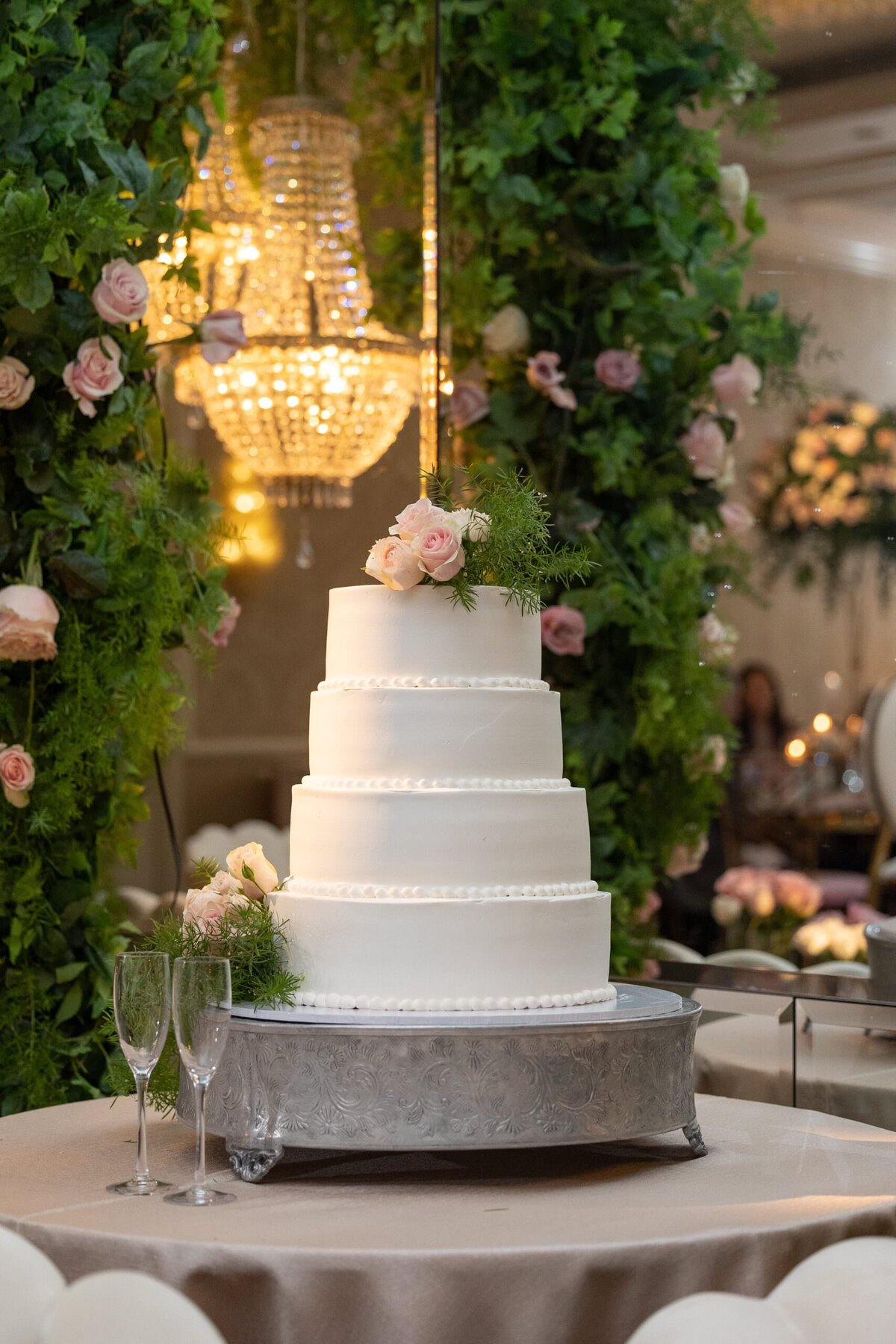 A four tiered wedding cake with pink flowers on top