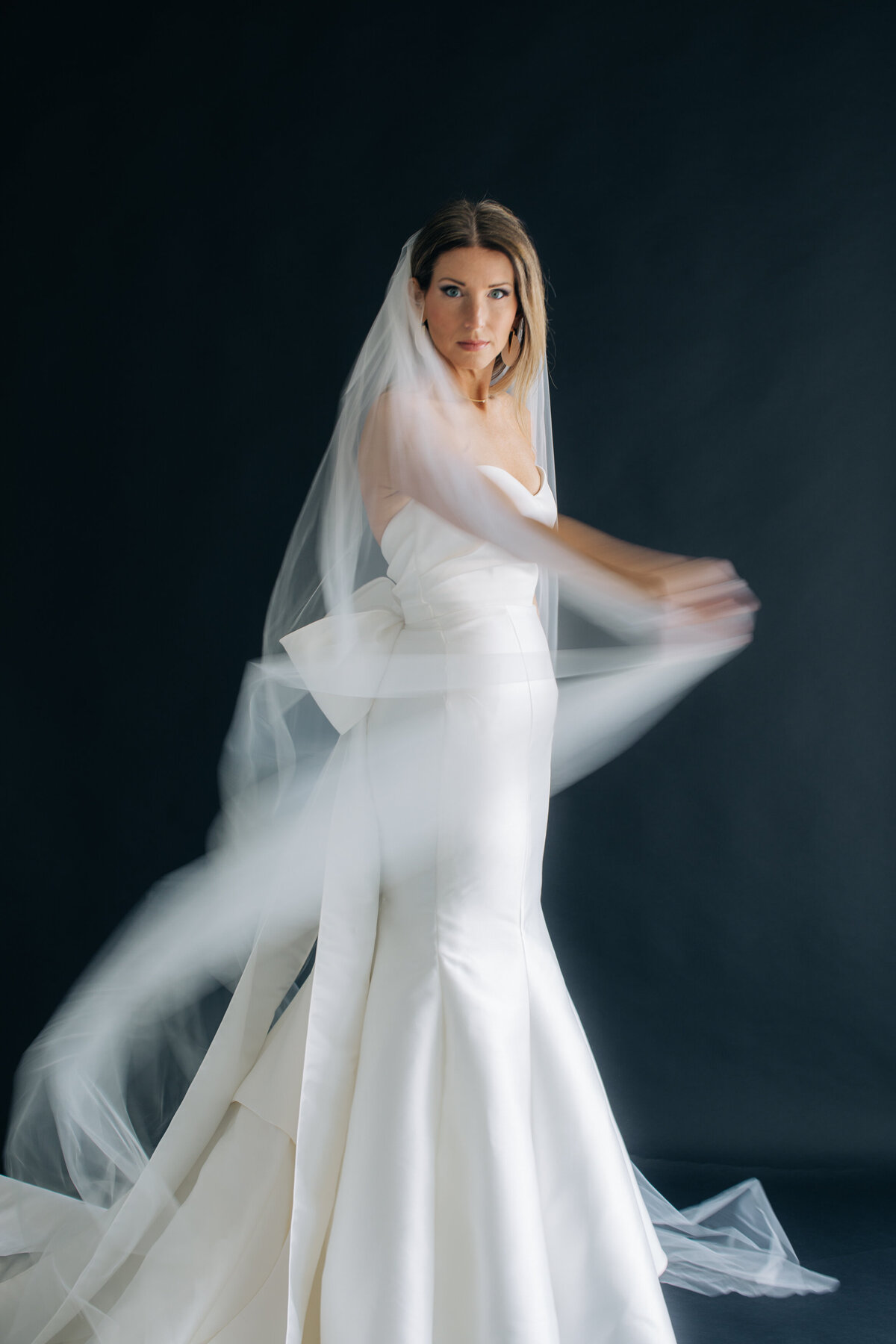 Woman in wedding dress twirling her veil.