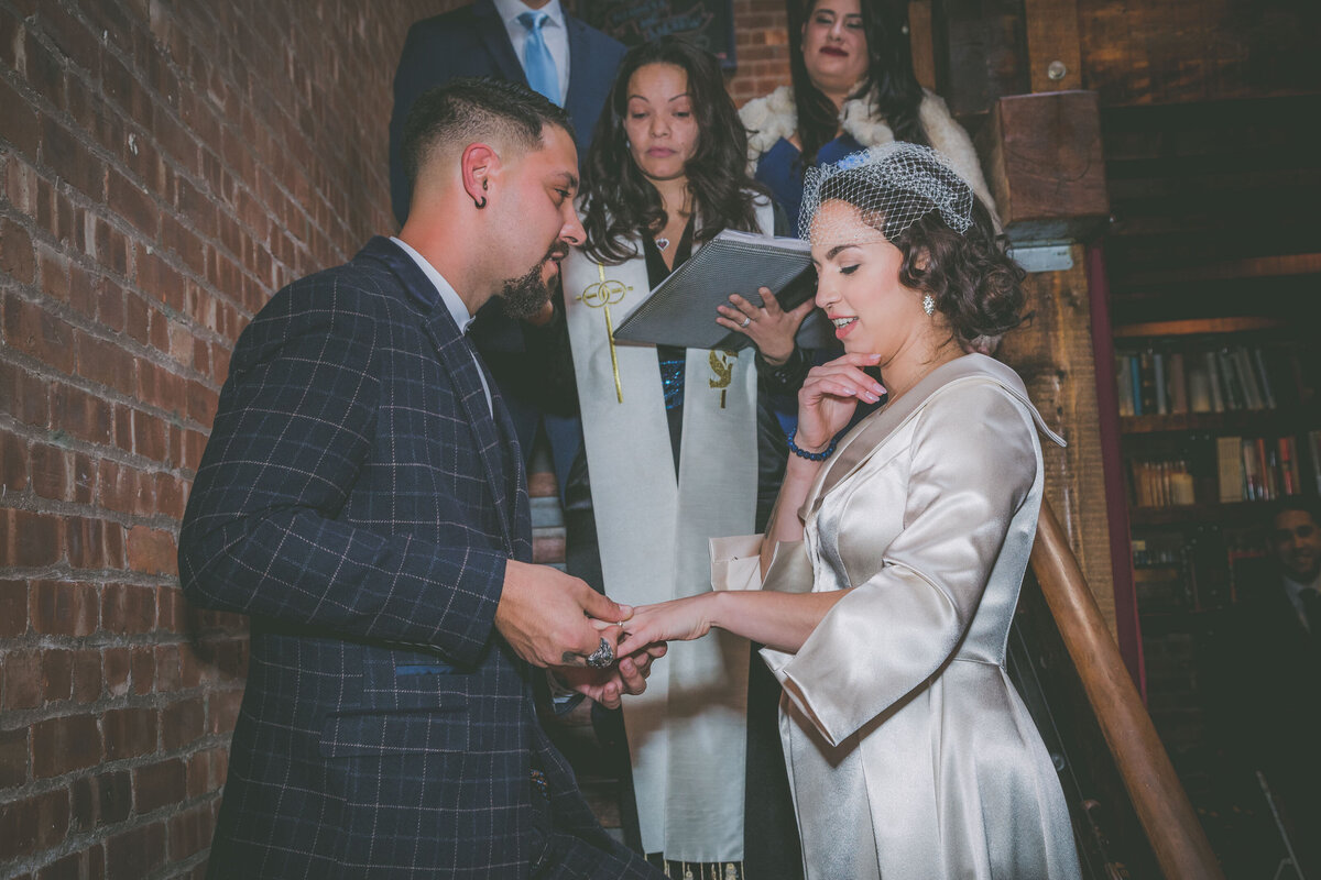 Groom puts ring on bride during the ceremony.