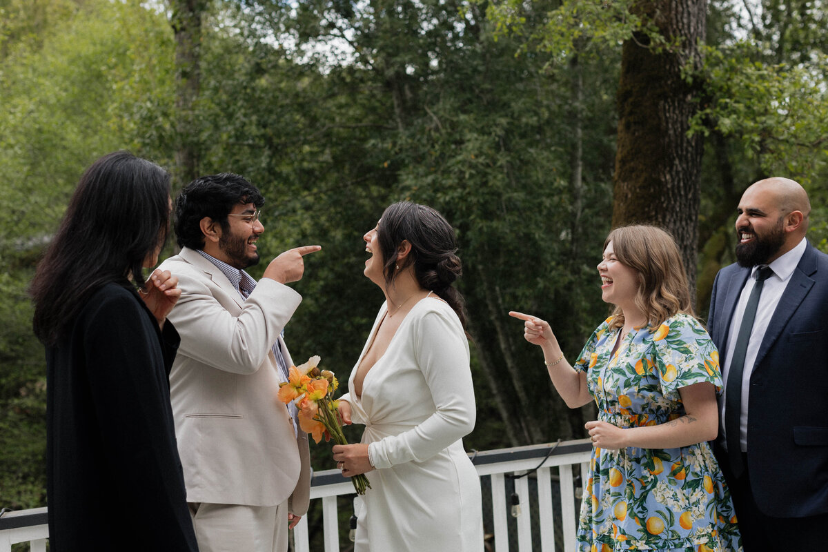 A joyful wedding moment featuring a bride in an elegant white gown laughing with friends during an outdoor celebration. We specialize in capturing natural, candid wedding photography that highlights authentic connections and storytelling. This intimate wedding reception moment showcases our approach to documentary-style wedding photography.