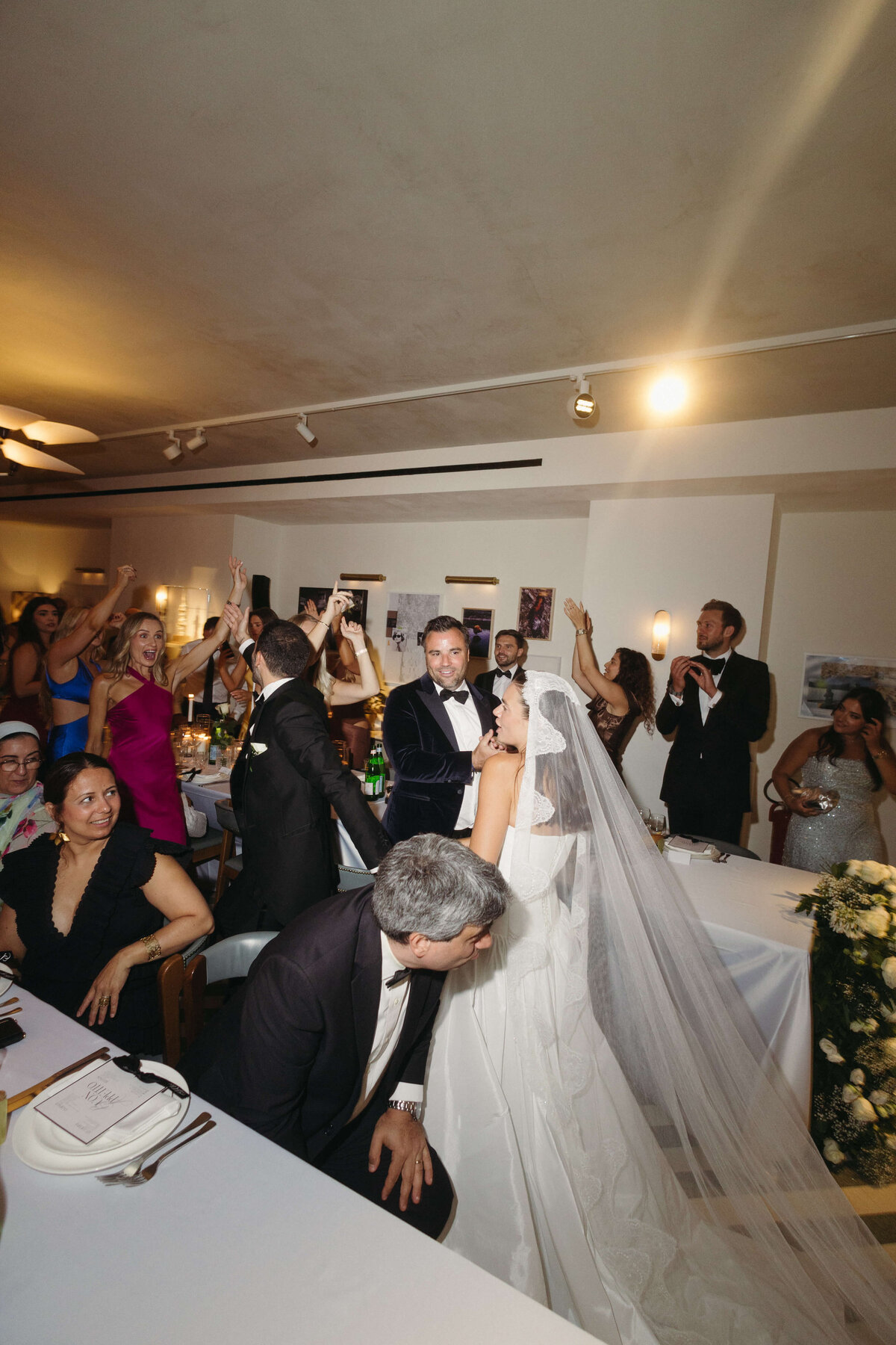 Guests clapping and cheering at candlelit dinner table during speech

