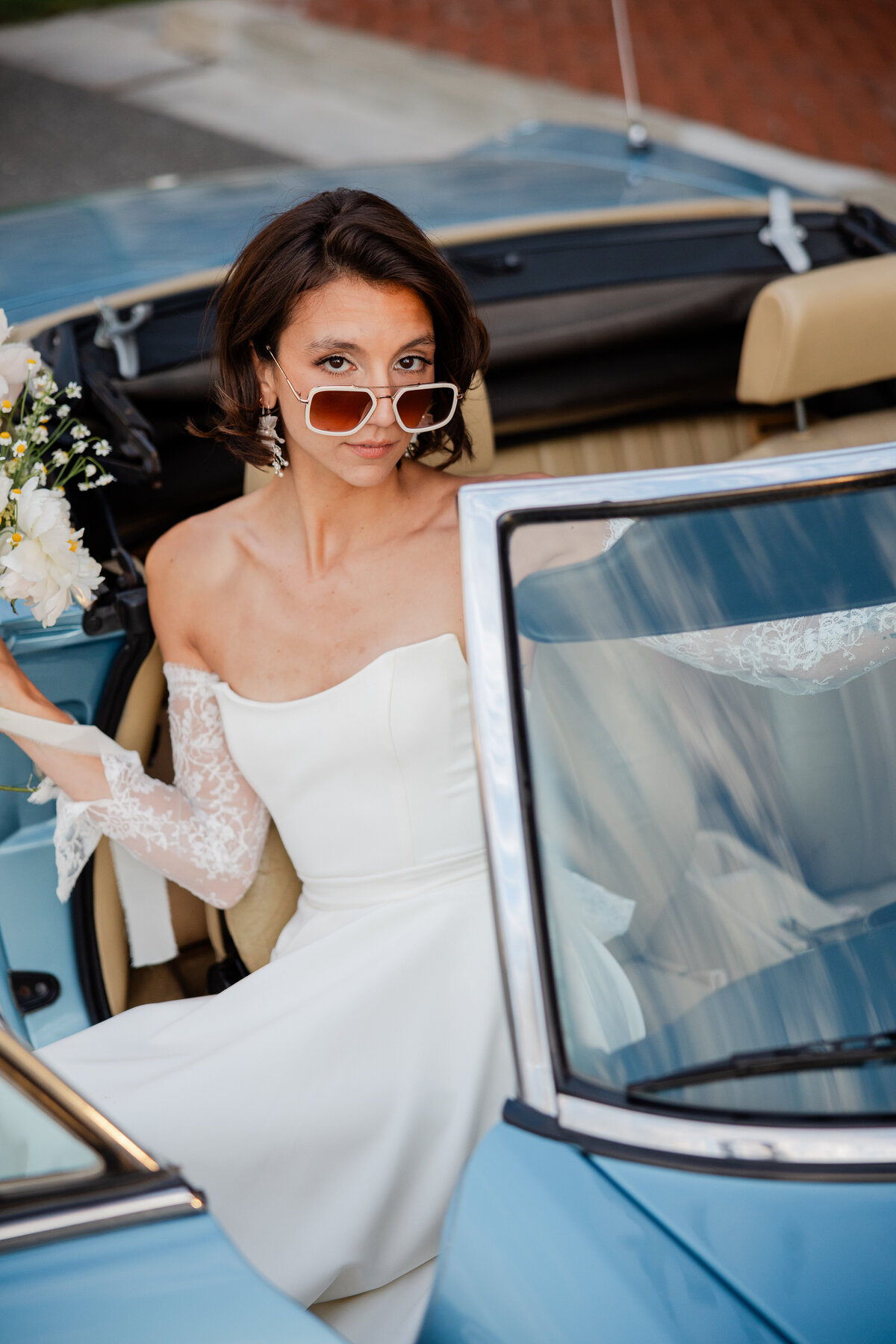 Photograph of a bride in a classic car.