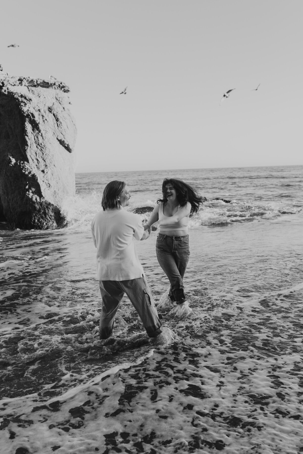 Joyful couple walking along the shore, Indiana beach engagement session.